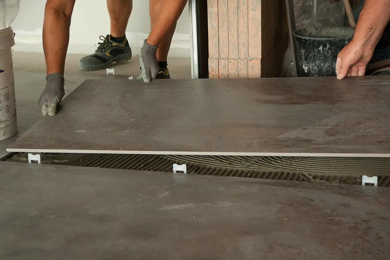 A tiler setting a large floor tile on adhesive