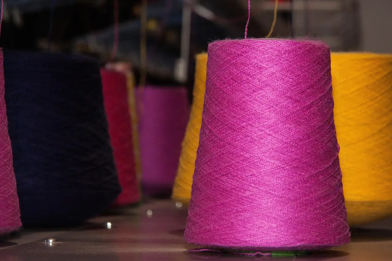 Cones of coloured yarn on a knitting machine