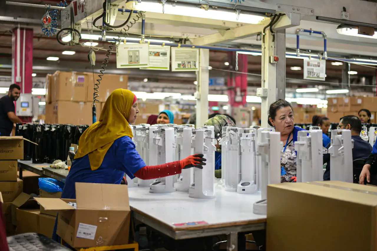 A worker packing products into boxes at a factory station