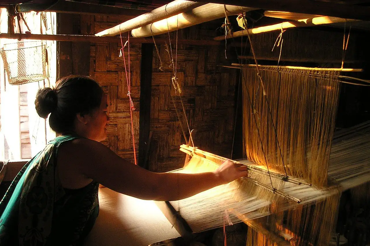 A woman working at a wooden handloom