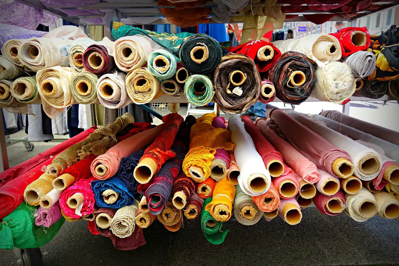 Rolls of coloured fabric stacked on shelves