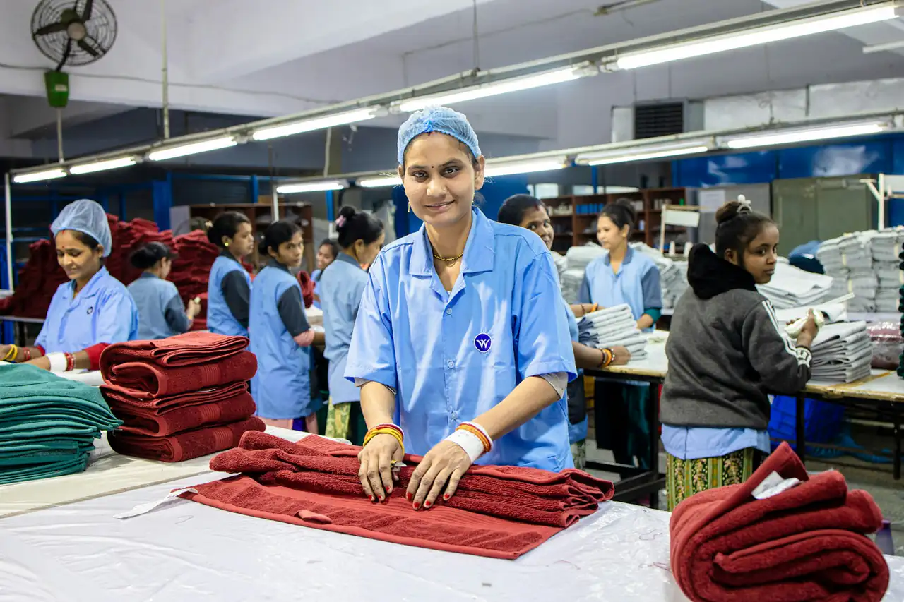 Workers in blue uniforms folding garments at factory tables