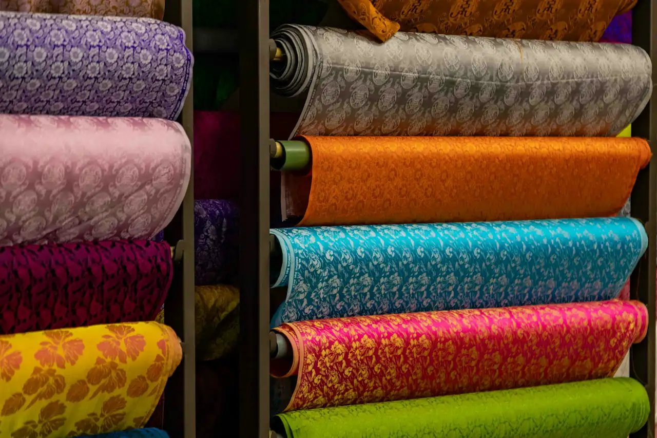 Rolls of coloured fabric on shelves